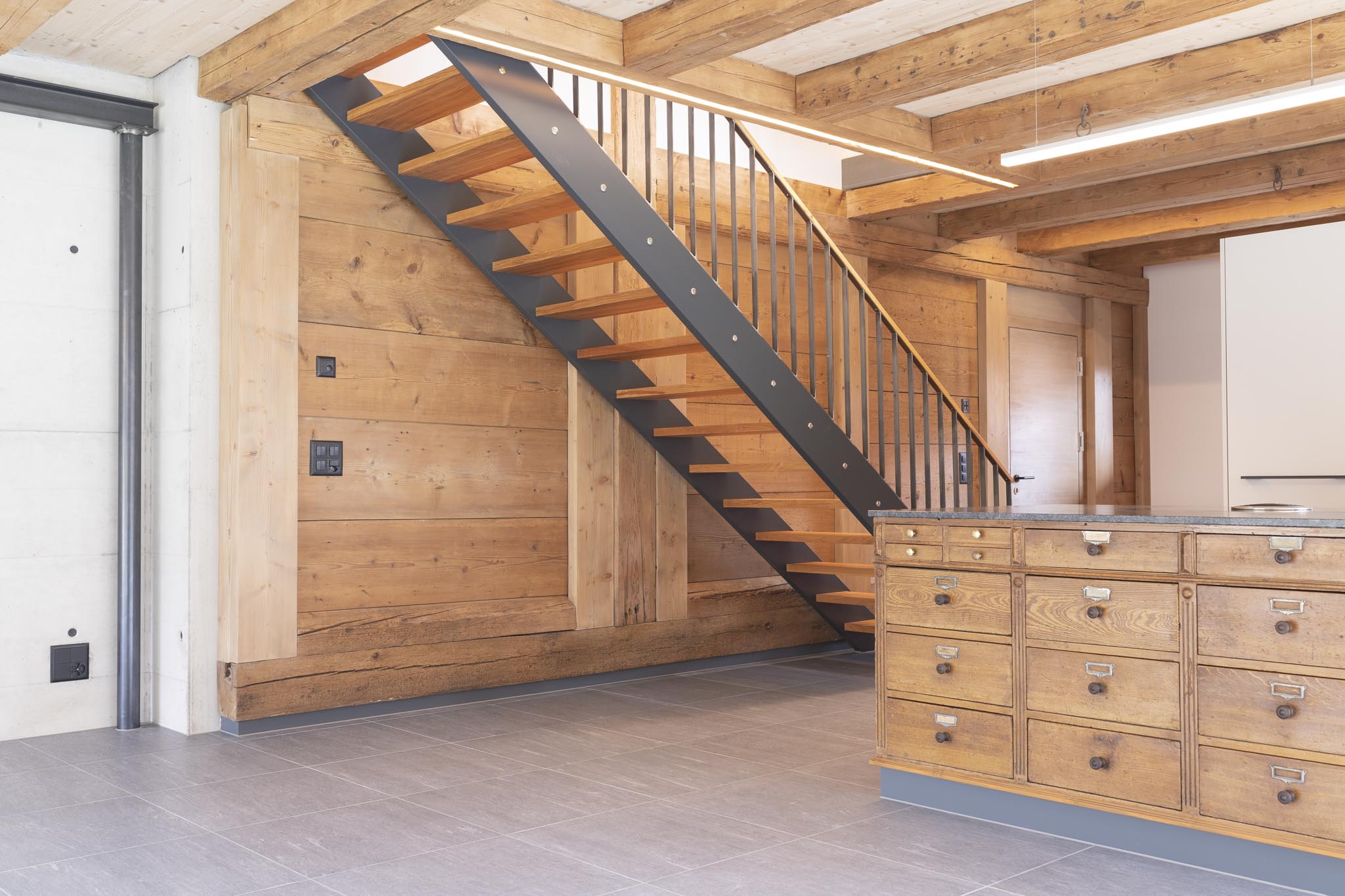 Traumhafte Küche eines umgebauten Bauernhauses die Tradition mit Modern vereint. Alte Holzelemente des rustikalen Bauernhauses wurden im neuen Raumkonzept integriert und mit modernen Elementen wie der Treppe in den oberen Stock und einem schönen Fliesenboden kombiniert. Die Kücheninsel wurde mit antiken vintage Schubladen ausgestattet um einen speziellen Charakter zu verleihen - geplant und realisiert durch die Kobi Architektur AG in Biezwil (Solothurn)